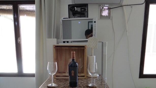 A kitchen with a granite countertop, a wine bottle, two wine glasses, and a microwave. - Beautiful Quiet Apartment Near Aristides (Mendoza)