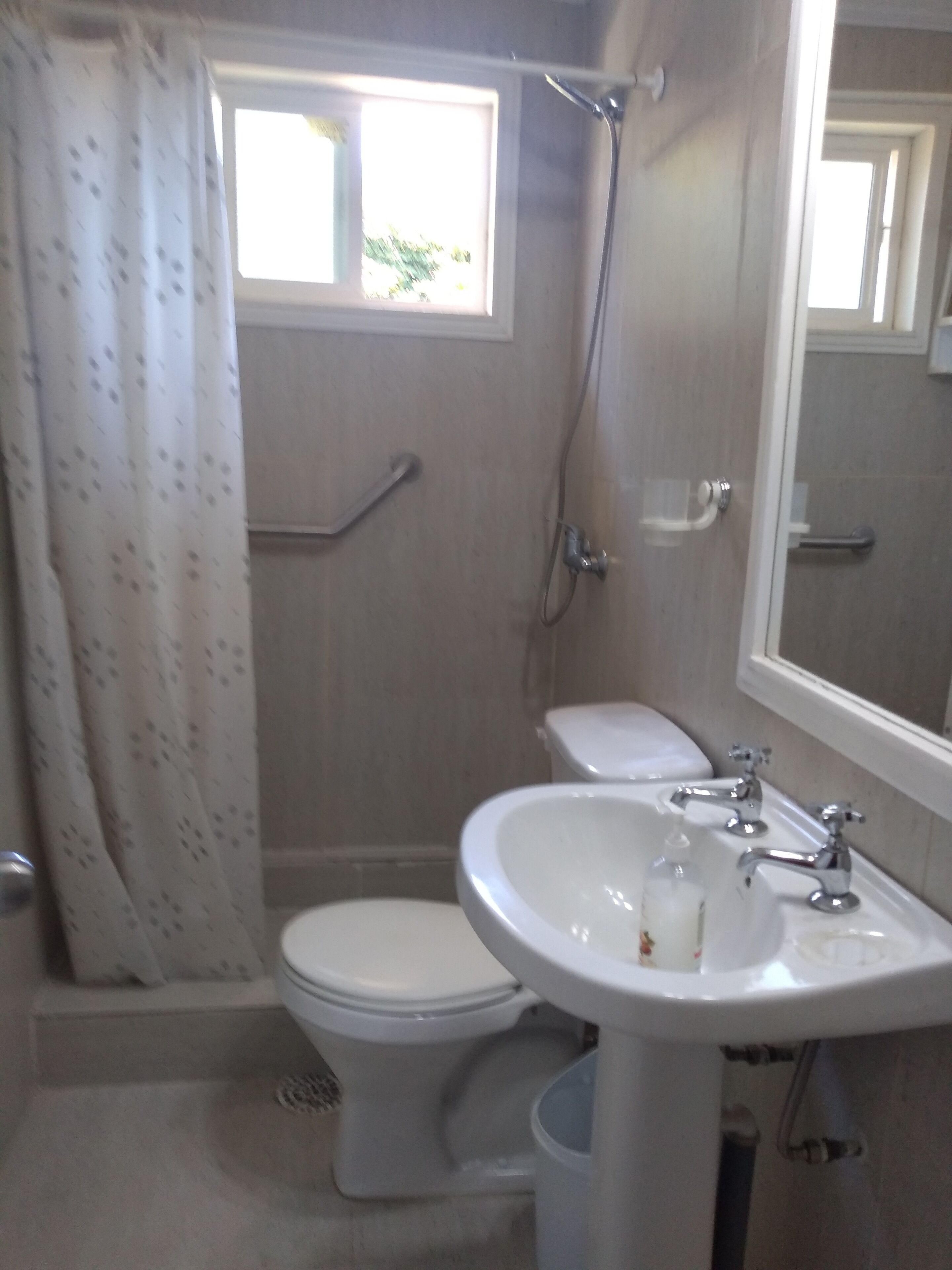 Een badkamer met toilet, wastafel, douche en raam.