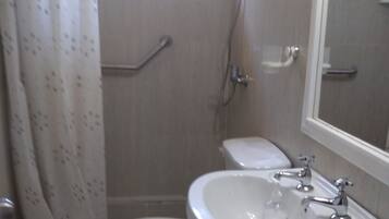 Een badkamer met toilet, wastafel, douche en raam.