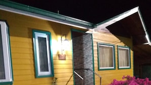 Un edificio amarillo con detalles verdes y una chimenea de piedra.