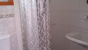 Une salle de bain avec un rideau de douche, des toilettes et un lavabo.
