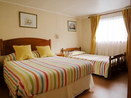 A double room with two beds, each with a colorful striped bedspread and a wooden headboard.