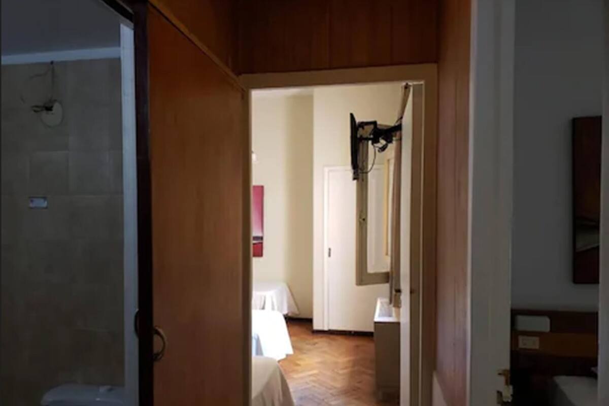 A hallway leading to a bedroom with a wooden floor, a white door, and a small table with a white tablecloth.