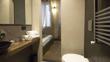 A compact bathroom with a sink, mirror, and towel rack.