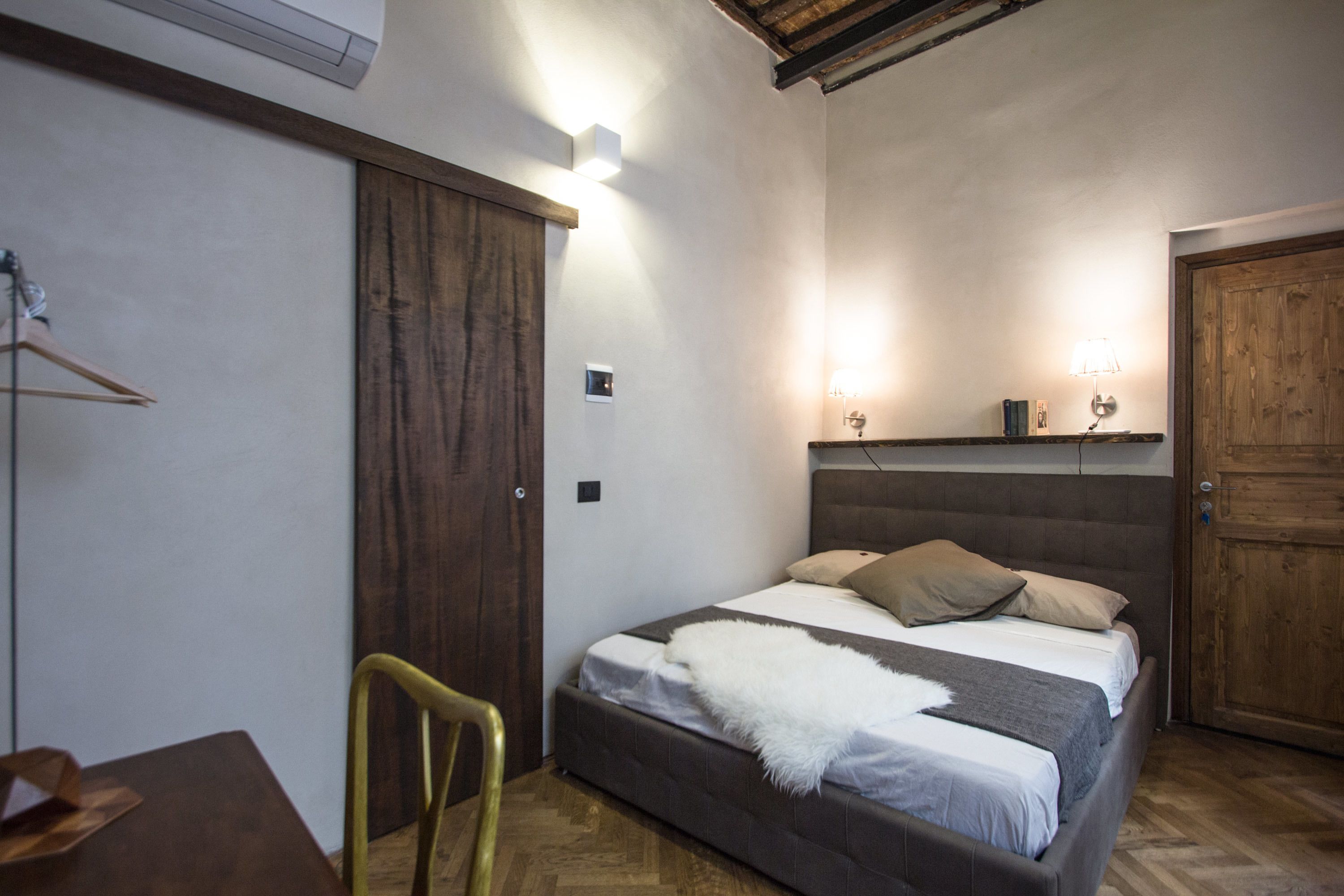 Une chambre à coucher avec un lit, une chaise, une armoire en bois et une porte.