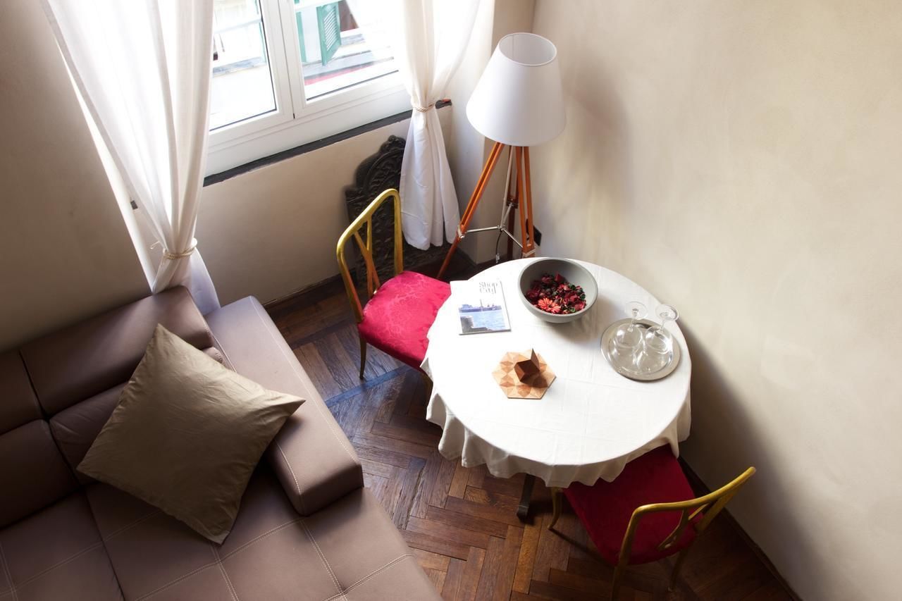 Una habitación acogedora con un sofá, una mesita con un frutero, una lámpara y una ventana con cortinas.