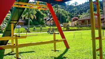 A playground with swings and climbing structures, surrounded by a well-maintained lawn and houses in the background.