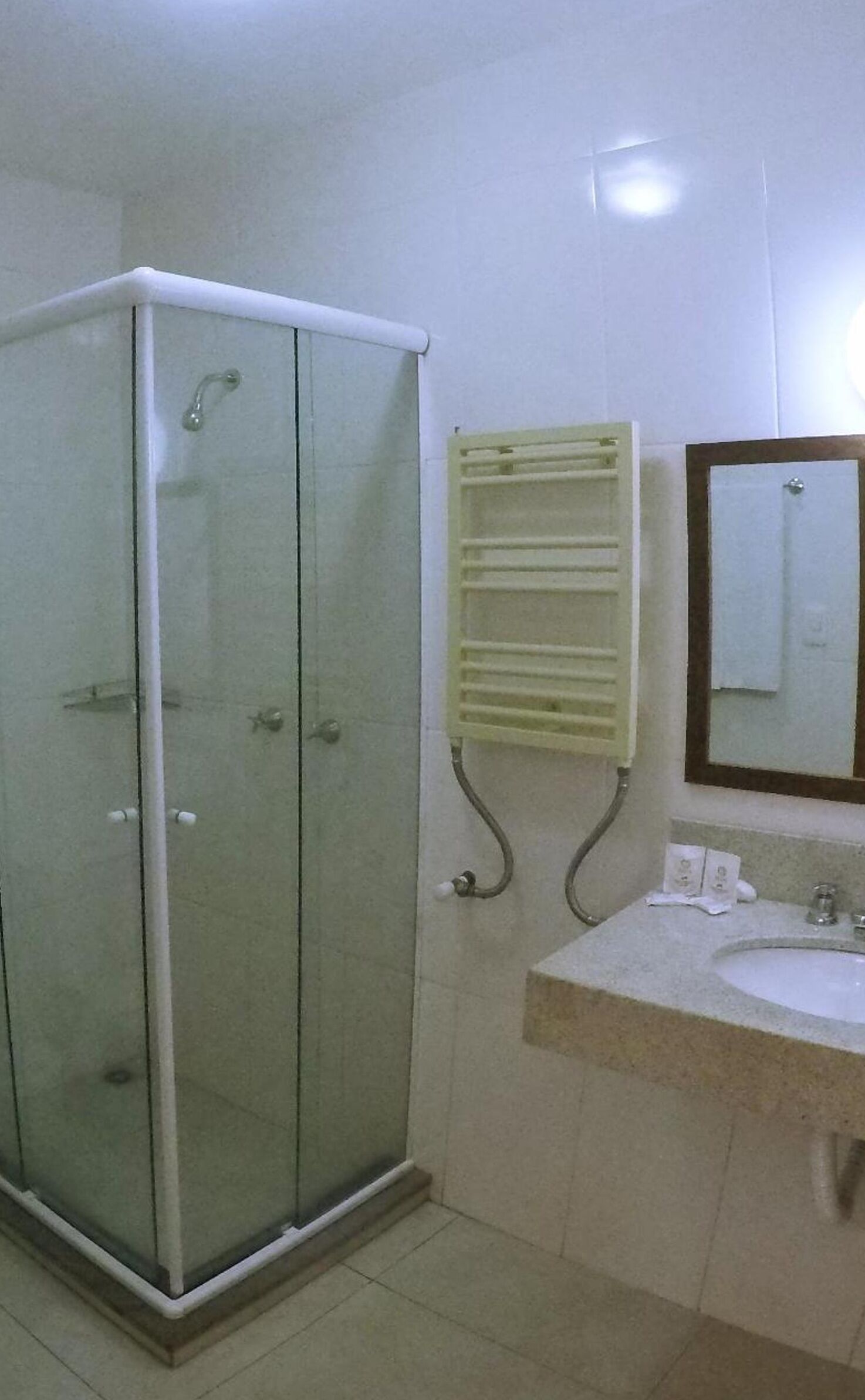 Une salle de bain avec une douche à parois de verre, un lavabo avec un miroir et un porte-serviettes.