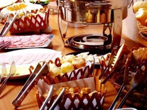 Una mesa de buffet con diversos alimentos y utensilios de servir.