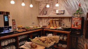 Un bufé de desayuno con diversas opciones de comida, una máquina de café y un dispensador de bebidas.