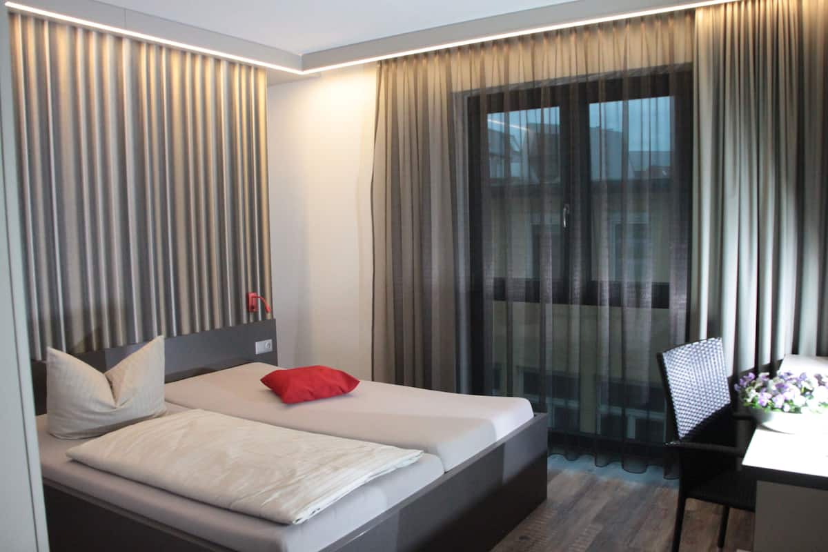 A hotel room with a bed, a desk, and a chair.