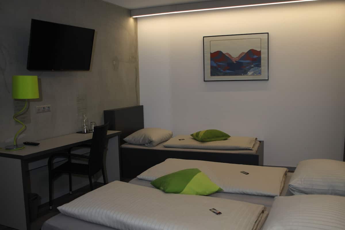 A hotel room with a bed, a desk, a chair, a TV, and a painting on the wall.