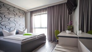 Una habitación de hotel moderna con una cama, un escritorio y un televisor.