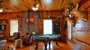A wooden interior with a pool table, leather chairs, a television, and mounted deer heads. - Southern Backroad Retreats (The Pool House) (Goshen)