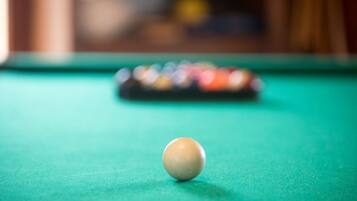 Una mesa de billar con una única bola blanca en foco y un juego de bolas de colores al fondo.