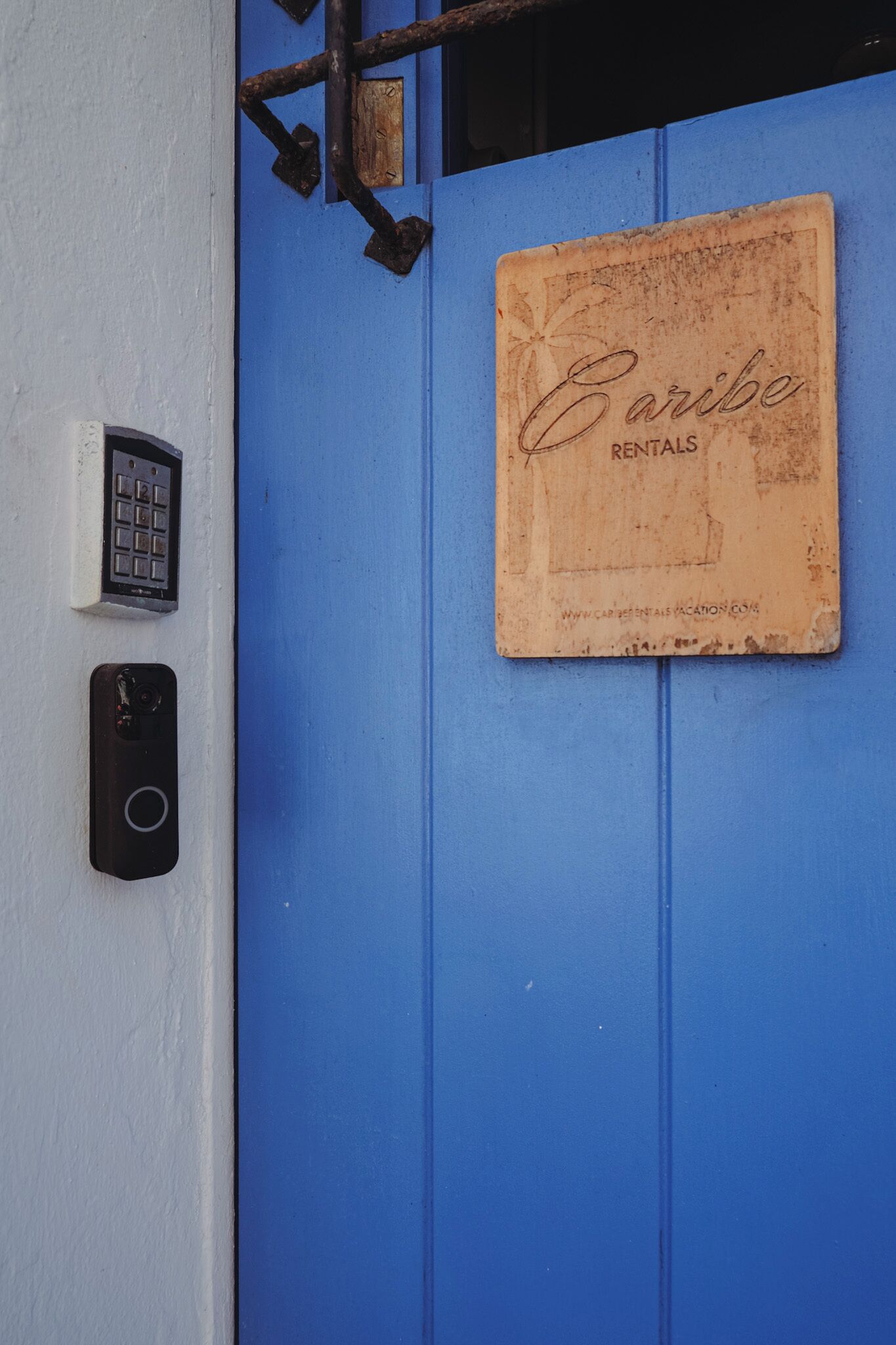 Eine blaue Tür mit einem Schild, auf dem 'Caribe Rentals' steht, und einem Zahlenschloss auf der linken Seite.