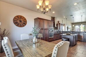 Une cuisine spacieuse avec des meubles en bois, une grande horloge et un coin repas comprenant une table et des chaises en bois.