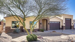 A residential building with a garage, a small patio area, and a desert landscape.