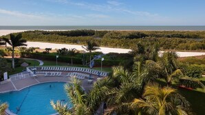 A pool with a view of the ocean, surrounded by palm trees and a sandy beach. - Beachfront 2BR/2BA Marco Island condo with pool, WiFi, and beach access. (Marco Island)