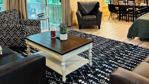 Un interior de madera con ventilador de techo, televisor, comedor y vistas al exterior.