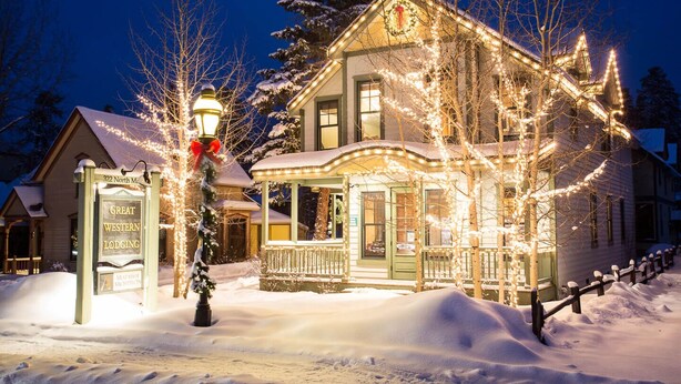A snow-covered building with a porch and a sign that reads "Great Western Lodging."