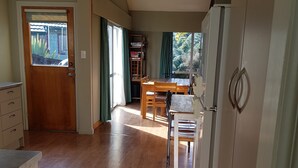 A spacious kitchen with wooden flooring, a dining area with a table and chairs, and a refrigerator. - Cosy spacious Chalet Experience. Beautiful views. (Hanmer Springs)
