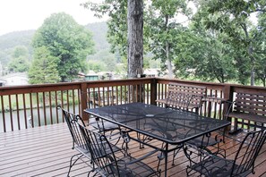 An outdoor deck with a metal table and chairs, surrounded by a wooden railing and trees. - Bring Your Boat:Private Ramp &Dock on HAMILTON-Fire Pit &Deck 4 Kings-sleeps 16  (Hot Springs)