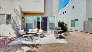 Une terrasse avec mobilier d’extérieur, un barbecue et une porte-fenêtre coulissante donnant sur un espace abrité.