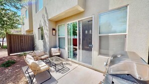 Une terrasse avec mobilier d’extérieur, un barbecue et des portes-fenêtres coulissantes.