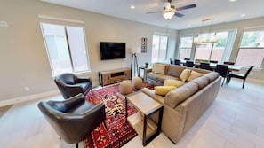 A modern living room with a sofa, chairs, a TV, and a dining area with a table and chairs. - Entrada at Moab - 424b, Spacious 4 Bed 3 Bath House (Moab)