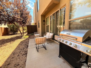 An outdoor patio with a barbecue grill, two wicker chairs, and a wooden fence. - Entrada at Moab - 424b, Spacious 4 Bed 3 Bath House (Moab)
