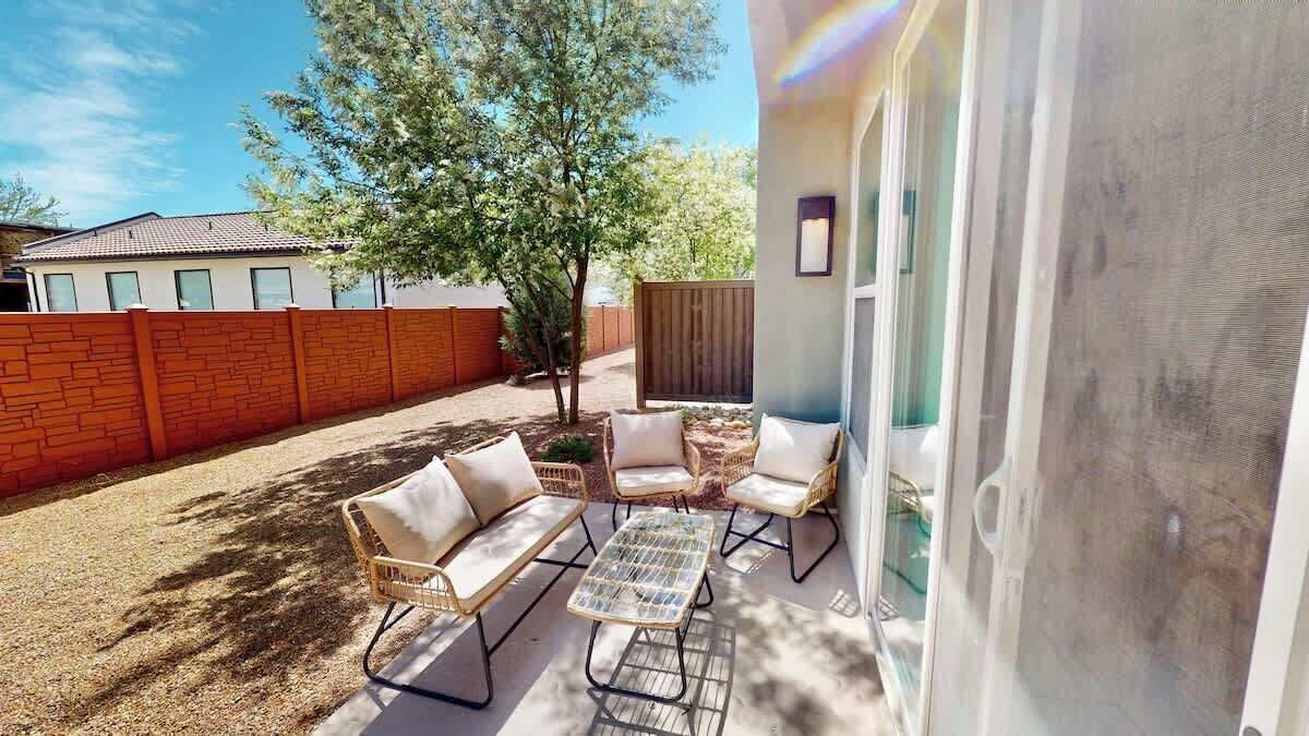 A patio with outdoor furniture, a tree, and a view of a neighboring house.
