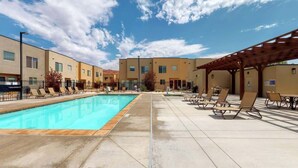 Un espace piscine avec des chaises longues et un coin salon abrité.