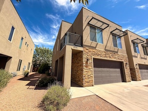 A modern two-story house with a stone facade, a garage, and a clear blue sky. - Entrada at Moab - 424b, Spacious 4 Bed 3 Bath House (Moab)