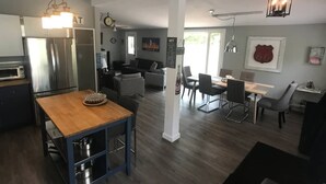 Una cocina moderna con una isla de madera, un comedor con mesa y sillas, y una sala de estar con sofá y mesa de centro.