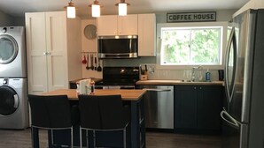 Una cocina compacta con una isla central, lavadora, microondas, cocina y refrigerador.