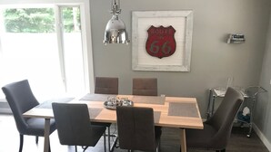 Un comedor con una mesa de madera, cuatro sillas, un letrero de Route 66 y una lámpara colgante.