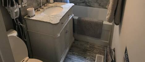 Un baño con lavamanos de mármol, inodoro, bañera y ducha.