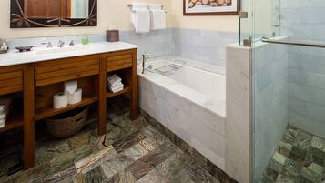 A bathroom with a wooden vanity, a bathtub, and a glass shower enclosure.