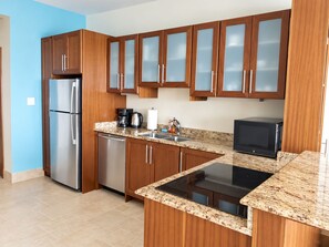 A modern kitchen with wooden cabinets, stainless steel appliances, and a granite countertop.