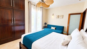 Un dormitorio con una cama, una mesita de noche, un sofá azul, un ventilador de techo y un armario.