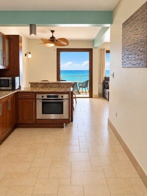A kitchen with a view of the ocean, a ceiling fan, and a dining area with a view.