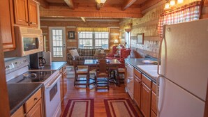 Una cocina acogedora de estilo cabaña con armarios de madera, una mesa de comedor y un refrigerador.