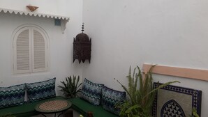 A cozy indoor seating area with a green sofa, patterned cushions, a small round table, and a decorative lantern.