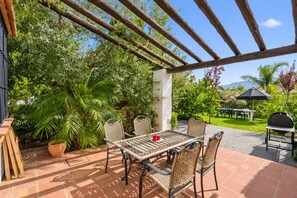 An outdoor patio with a pergola, a table with chairs, a grill, and lush greenery. - Cubo's Casa La Viña / private pool / air conditioning / free wifi (Alhaurín el Grande)