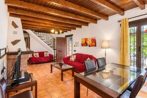 A living room with a red sofa, a glass coffee table, a TV, and a staircase. - Cubo's Casa La Viña / private pool / air conditioning / free wifi (Alhaurín el Grande)