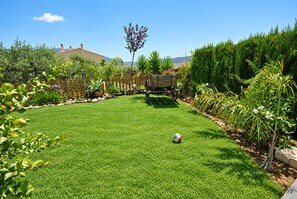 A well-maintained backyard with a grassy lawn, a wooden play structure, and various plants.