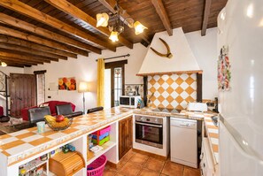 A kitchen with wooden beams, a checkered countertop, a microwave, an oven, and a refrigerator. - Cubo's Casa La Viña / private pool / air conditioning / free wifi (Alhaurín el Grande)