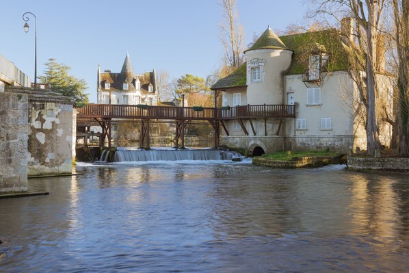 Un puente histórico sobre un río tranquilo, con un edificio de estilo castillo al fondo.