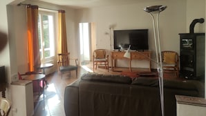 Ein Wohnzimmer mit Sofa, Fernseher, Lampe und Kamin.